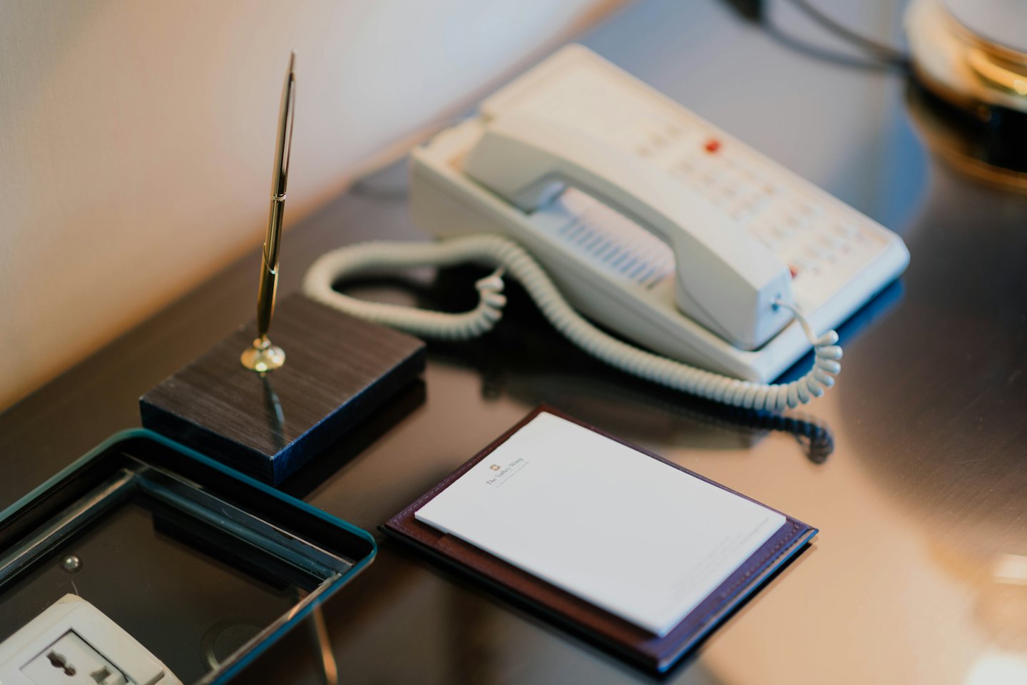 Hotel desk with telephone, pen, and notepad.