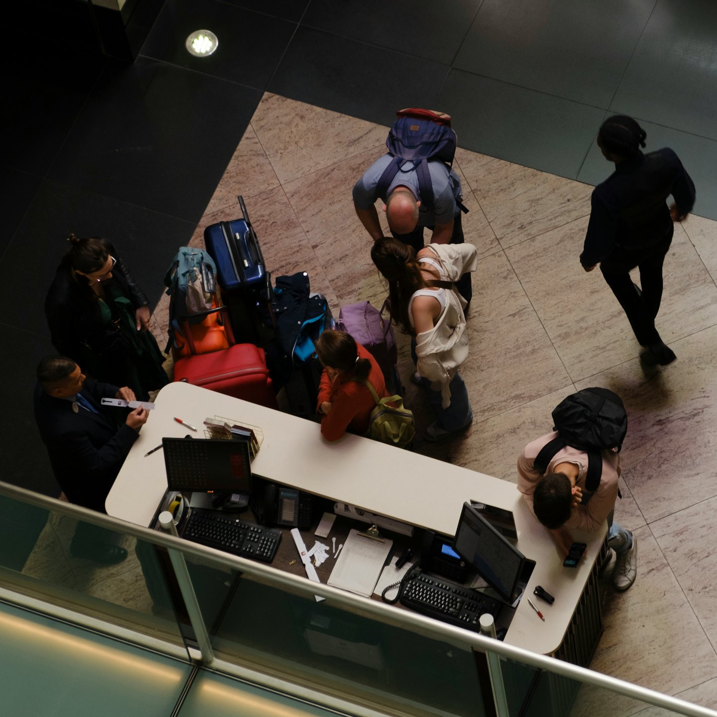 Travelers check in with airport staff at a service counter.