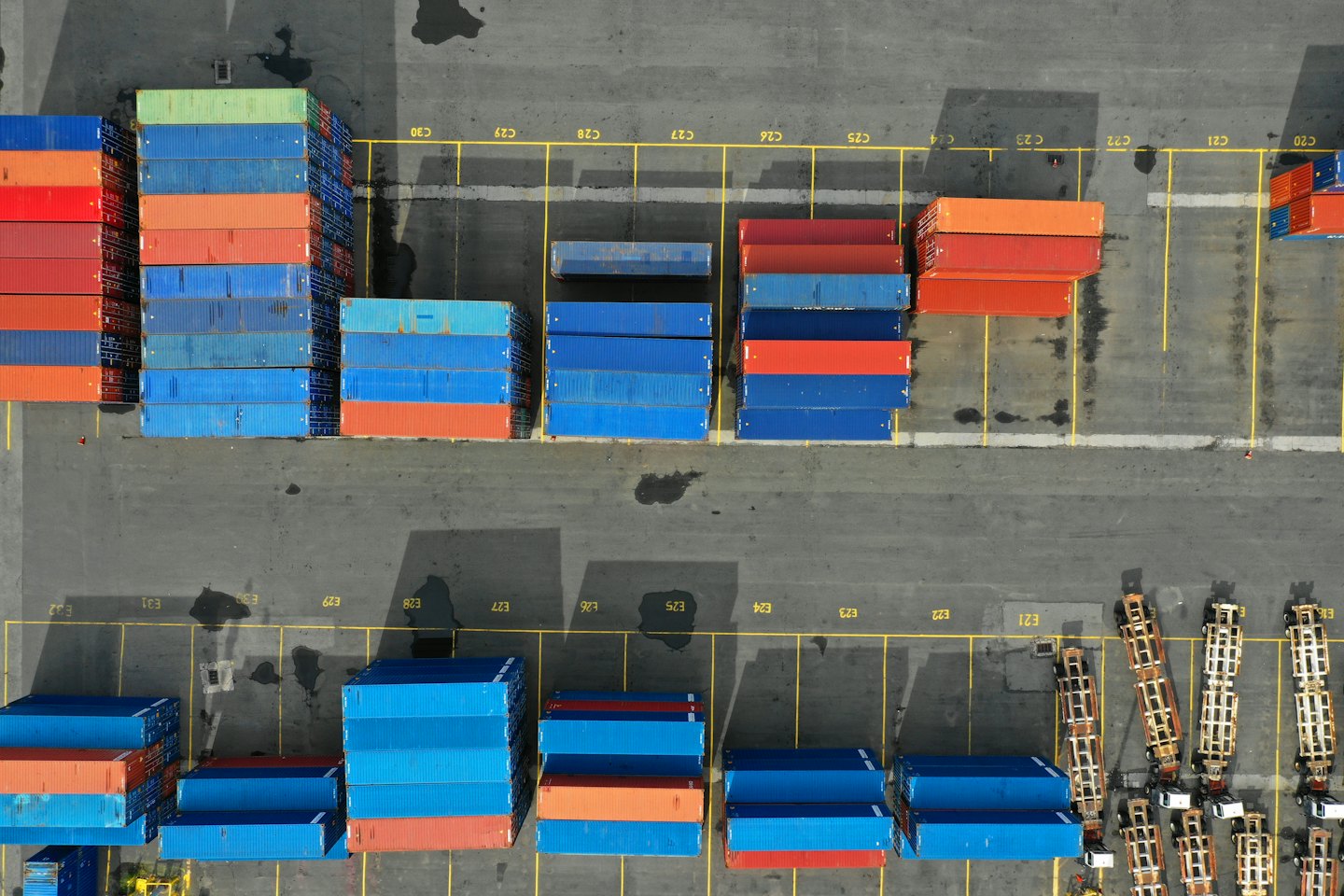 Aerial view of a busy logistics hub with stacked blue and red shipping containers.
