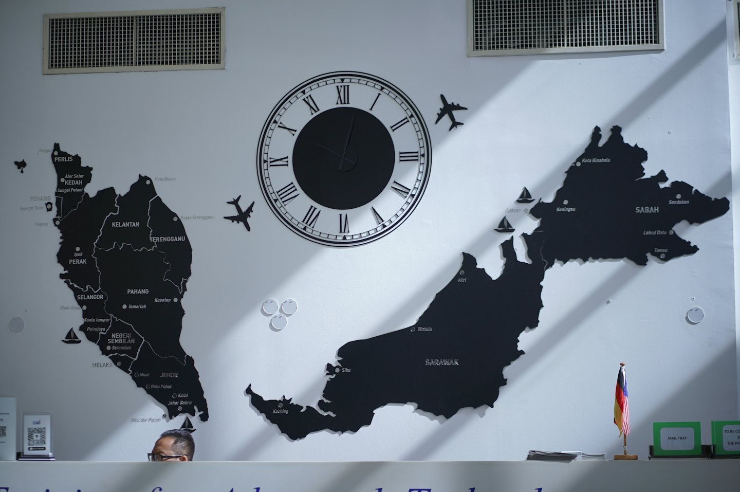 A person looks over a counter featuring maps of Malaysia.